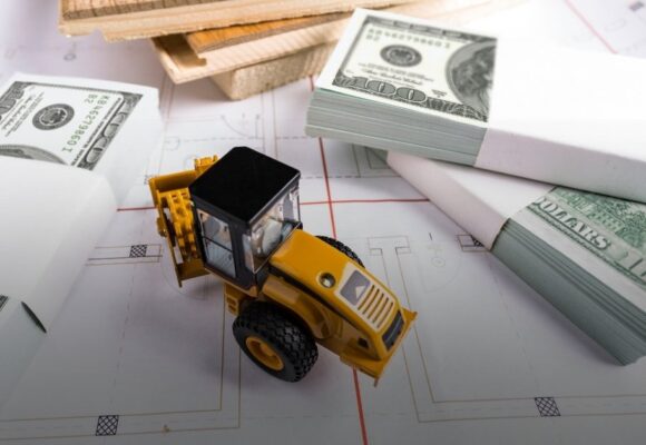 Image of a toy backhoe surrounded by lumber and money