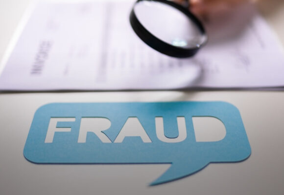 Image of a magnifying glass looking at an invoice with the word 'Fraud' highlighted in