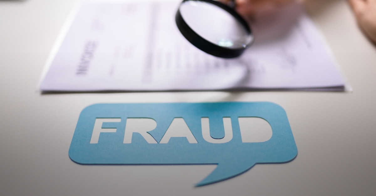 Image of a magnifying glass looking at an invoice with the word 'Fraud' highlighted in