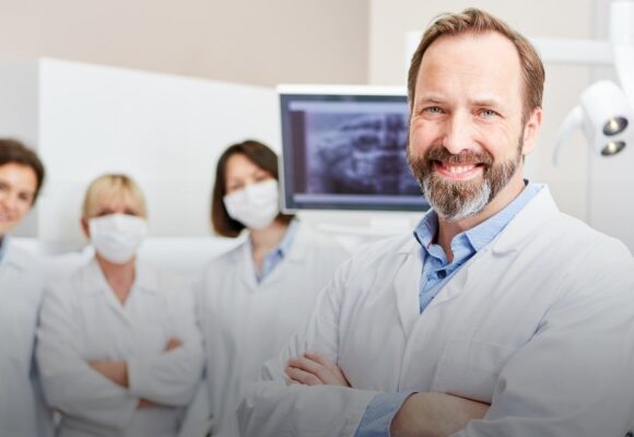 Image of an older dentist with his staff