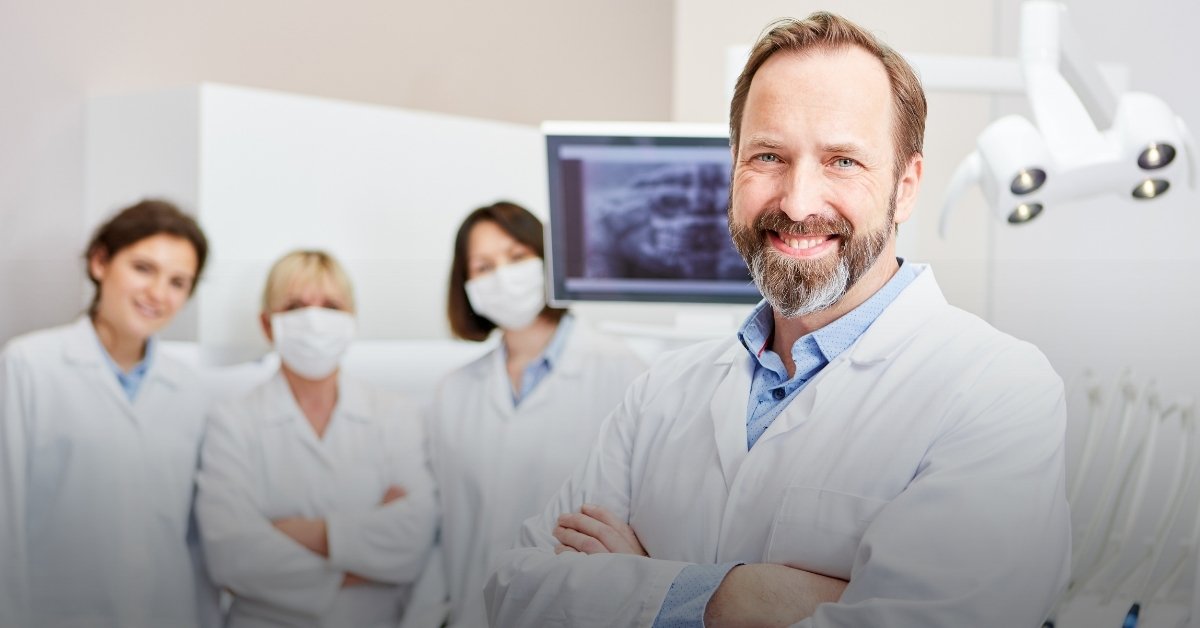 Image of an older dentist with his staff