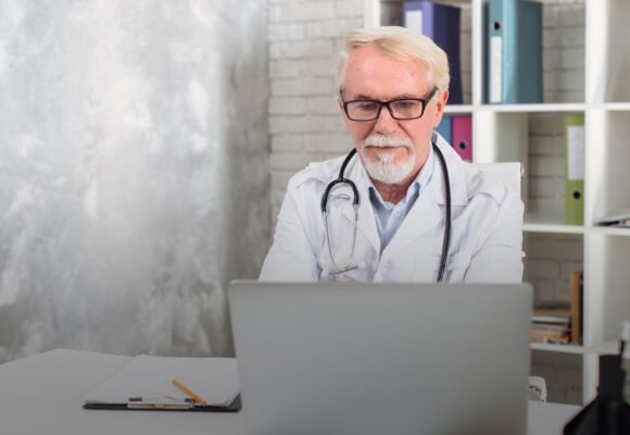 Image of an older doctor researching on his laptop