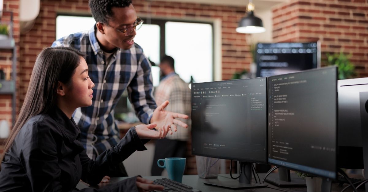 Image of two people talking at a computer desk