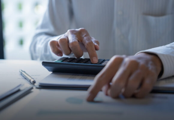 Image of a person at a desk, running numbers with a calculator