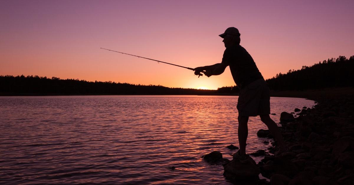 Image of a retired person fishing on a lake at sunset